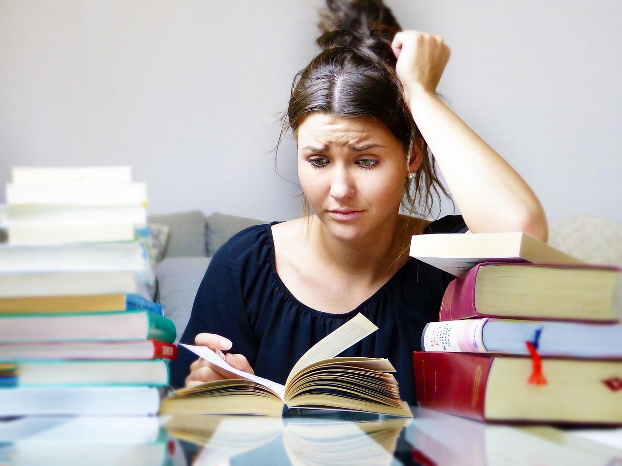 Mujer tratando de aprender idiomas mediante la lectura de manuales y libros de texto, se desespera al no conseguirlo